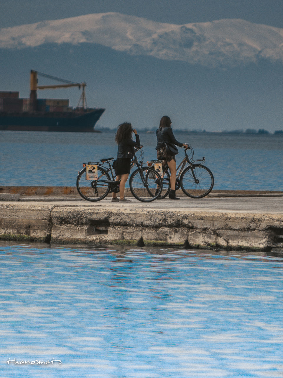 PEOPLE RIDING BICYCLE ON SEA AGAINST SKY