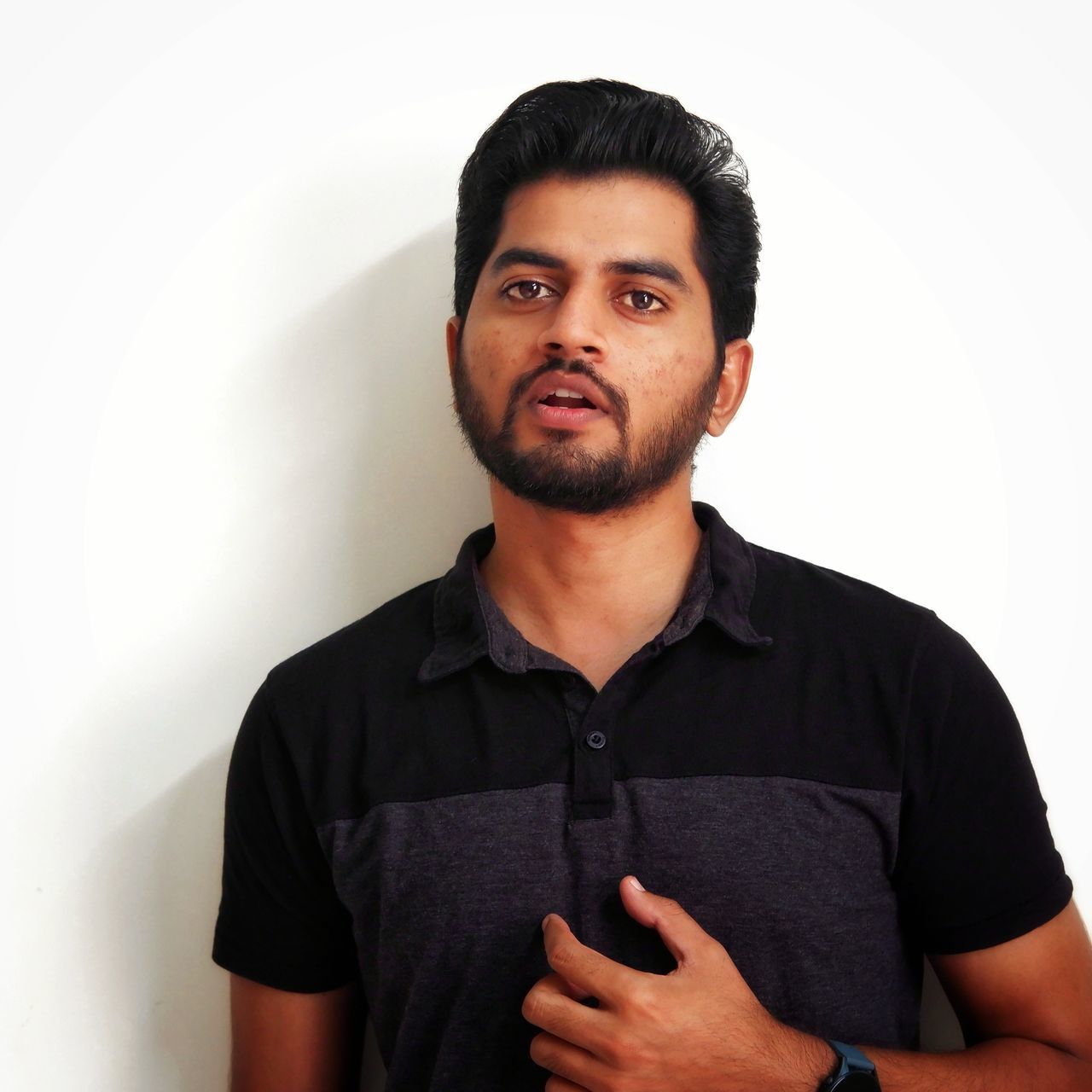 one person, portrait, beard, adult, men, facial hair, looking at camera, casual clothing, young adult, indoors, waist up, studio shot, sleeve, front view, t-shirt, white background, standing, hairstyle, looking, clothing, collar, person, serious, photo shoot, black hair, emotion, cool attitude, relaxation, stubble, copy space, black, arms crossed, polo shirt, lifestyles, individuality, contemplation