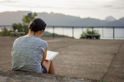 Woman reading book while sitting on steps