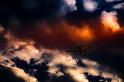 Low angle view of airplane flying against sky during sunset