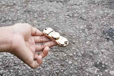 Cropped hand holding fidget spinner on road