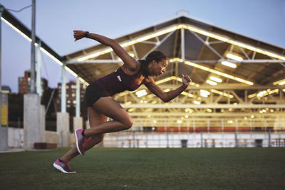 Female athlete practicing on field during sunset