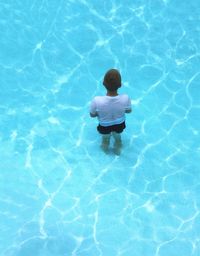 High angle view of boy standing in swimming pool