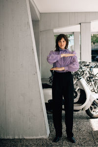 Portrait of young woman gesturing equal sign while standing in parking garage