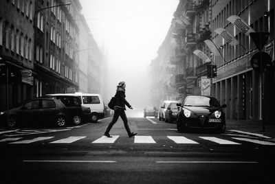 Man crossing road amidst buildings in city
