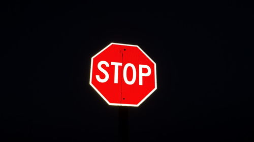 Close-up of neon light bulb over black background