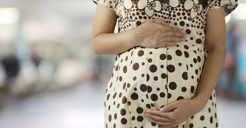 Midsection of woman standing by tree against blurred background