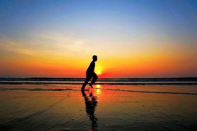 Silhouette man on beach against sky during sunset