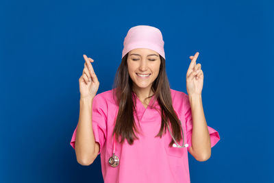 Portrait of smiling young woman holding pink against blue sky