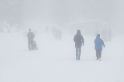 People on snow covered landscape against sky