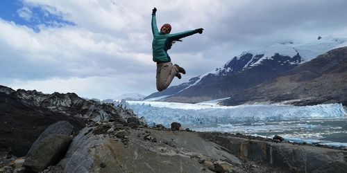 Man standing on rock by sea against sky