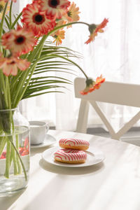 Romantic breakfast in the kitchen with a bouquet of flowers, donuts, coffee and fresh strawberries. 