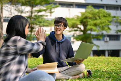 Young woman using laptop while sitting on field