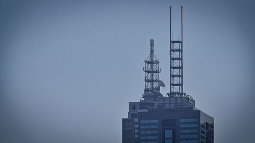 Low angle view of crane by building against clear sky