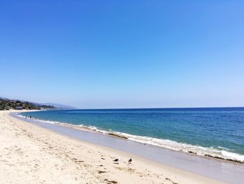 Scenic view of beach against clear blue sky