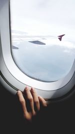 Cropped hand of person on airplane window