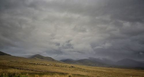 Scenic view of landscape against storm clouds