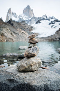 Stack of rocks by lake against snowcapped mountains and glacier