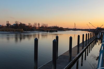 Wooden posts in river at sunset