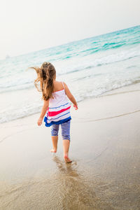 Rear view of girl walking at beach