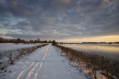 Scenic view of snow covered land against sky during sunset