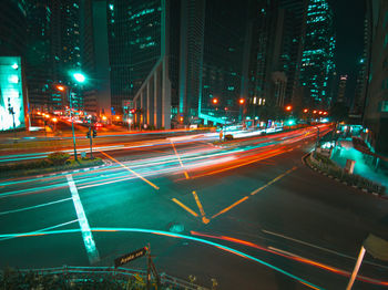 Light trails on city street by buildings at night