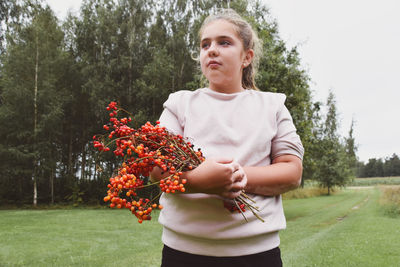 Portrait of teenage girl holding plant on field