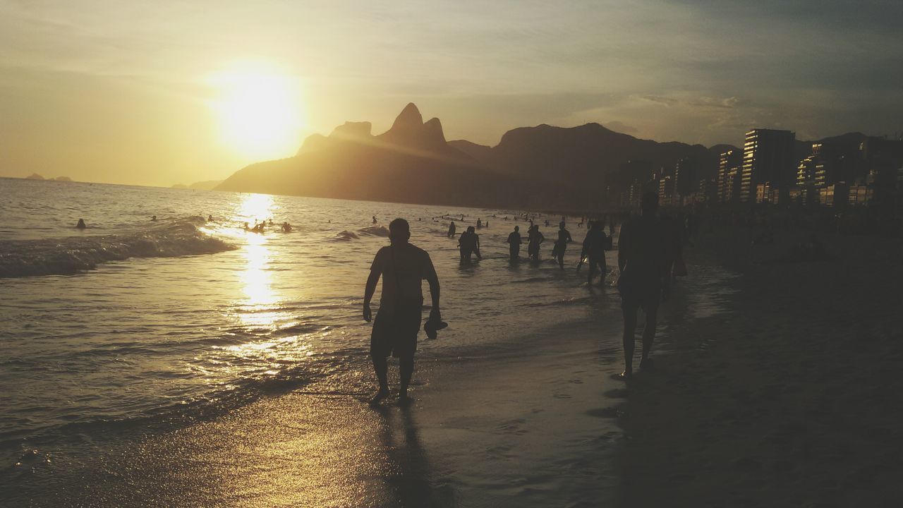 water, sunset, sea, beach, silhouette, lifestyles, sun, leisure activity, shore, reflection, sky, scenics, sunlight, beauty in nature, men, person, tranquil scene, nature, standing