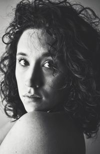 Close-up portrait of shirtless woman with short curly hair