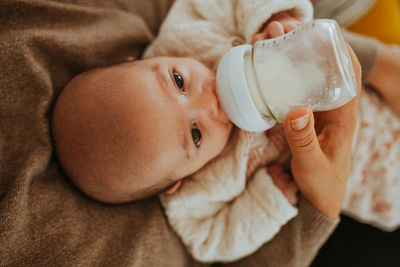 High angle view of mother feeding baby boy while sitting at home