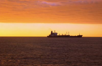 Boat sailing in sea at sunset