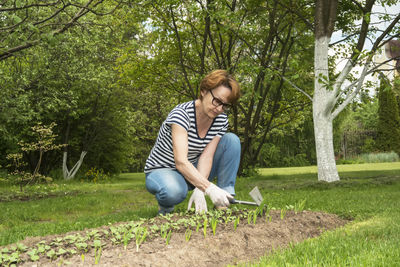 Full length of man sitting on grass against trees