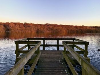 Pier over lake against clear sky