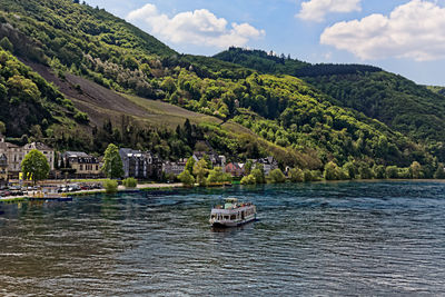 Boat sailing on river by trees against sky