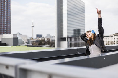 Young woman in the city wearing headphones, dancing