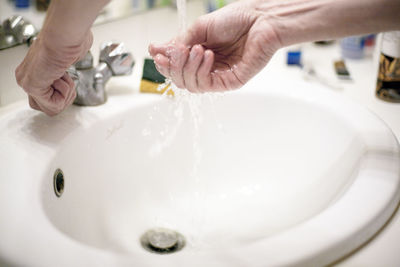 Close-up of hand touching water in bathroom