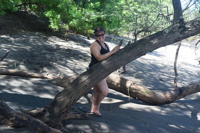 Portrait of young woman sitting on tree trunk