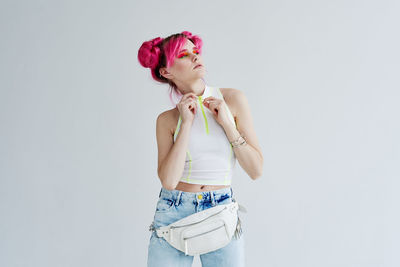 Portrait of young woman standing against white background