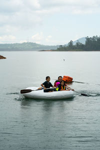 People in boat on shore against sky