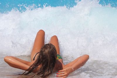 Girl on shore at beach against waves