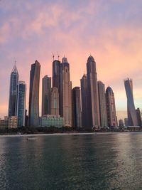 River by dubai marina in city against cloudy sky during sunset