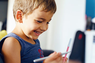 Close-up portrait of smiling boy using mobile phone