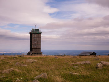 Lighthouse on field against sky at sunset