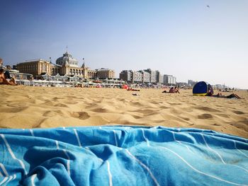 View of beach with buildings against clear blue sky