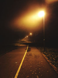 Empty road along illuminated street lights at night