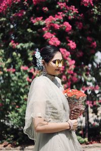 Side view of a smiling young woman standing against plants