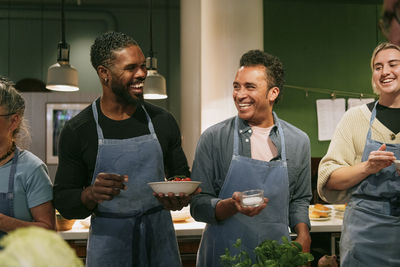 Multiracial students laughing during cooking class in kitchen