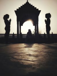 Silhouette people standing at seaside against sky