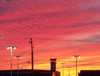 Low angle view of street lights against orange sky