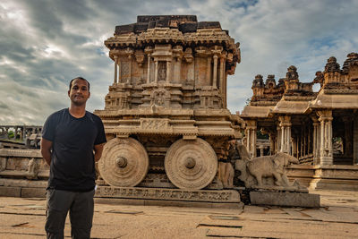 Man standing in front of historical building against cloudy sky